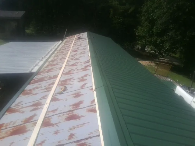 Old rusted panels beside newly installed green metal roofing — Wind Damage Roof Repair by Roofing Brothers in Park Forest