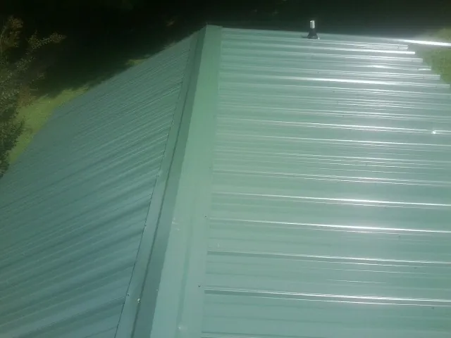 New green metal panels meeting at the ridge of a roof — Flat Roof Repair work by our crew in Park Forest