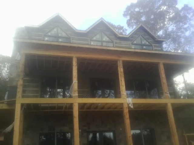 Dormers and porch framing on a large log home under construction — Roof Coating work by our crew in Park Forest