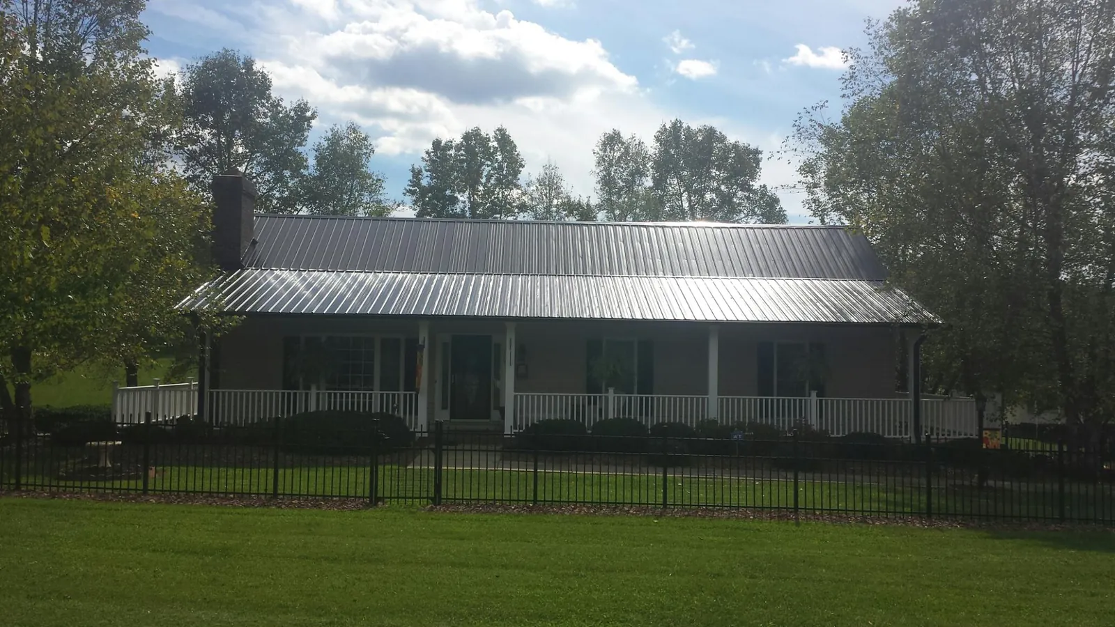 Gray metal roof on a brick ranch with a full width front porch — Gutter Guard Installation work by our crew in Park Forest