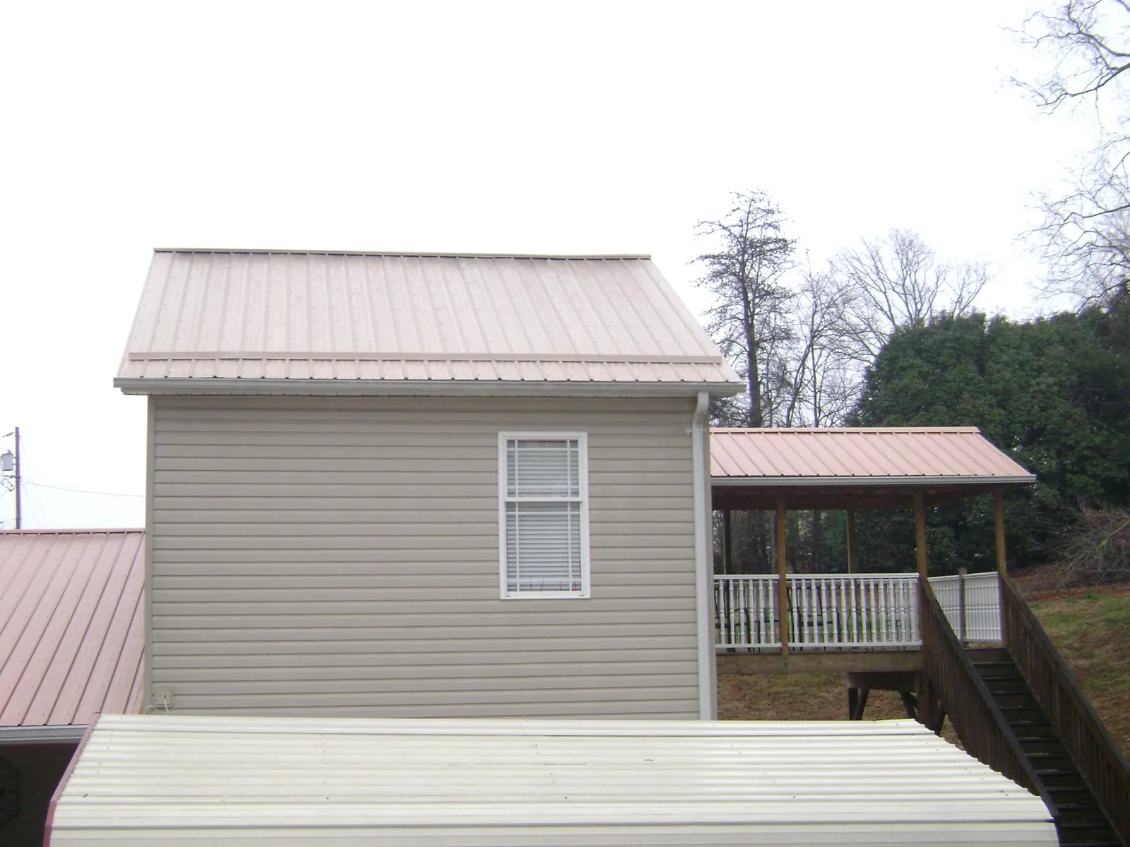 Tan metal roofs on a two story addition and attached porch, from a Roof Replacement job in Park Forest