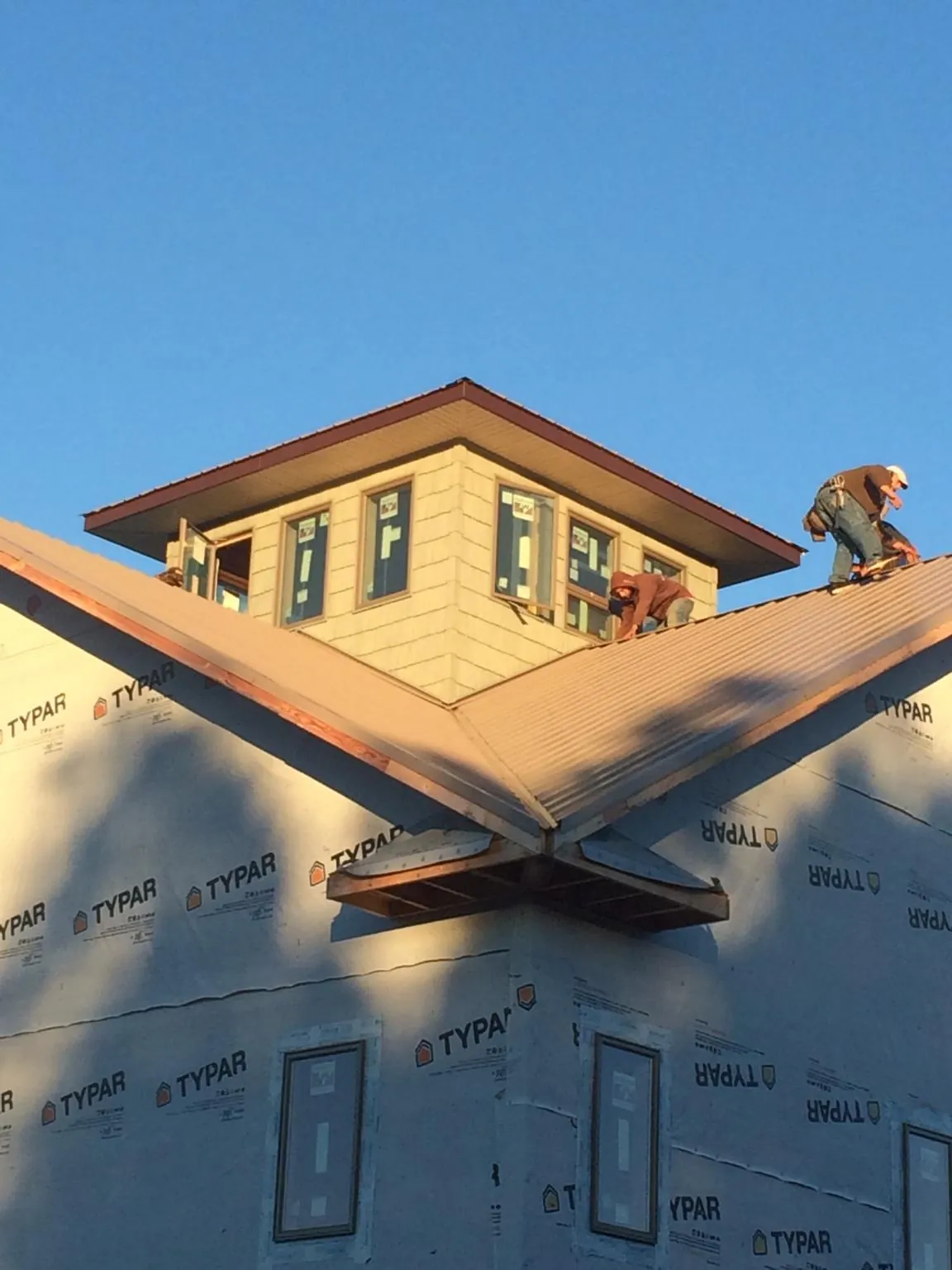Roofers working around a rooftop cupola on a new metal roof at sunset — Roof Waterproofing in Park Forest by Roofing Brothers